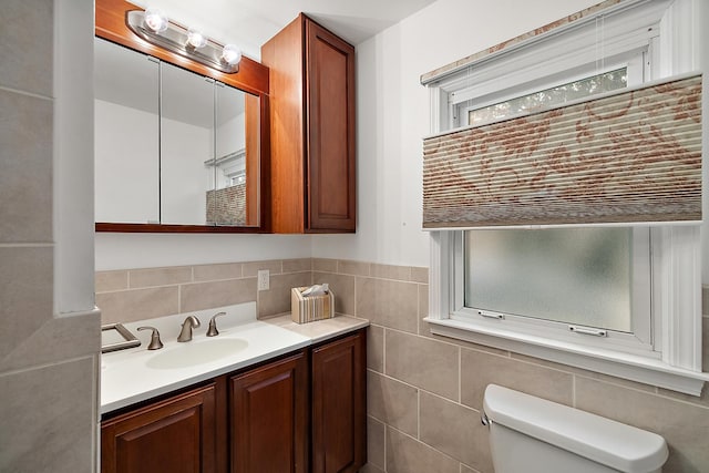 bathroom featuring vanity, tile walls, and toilet