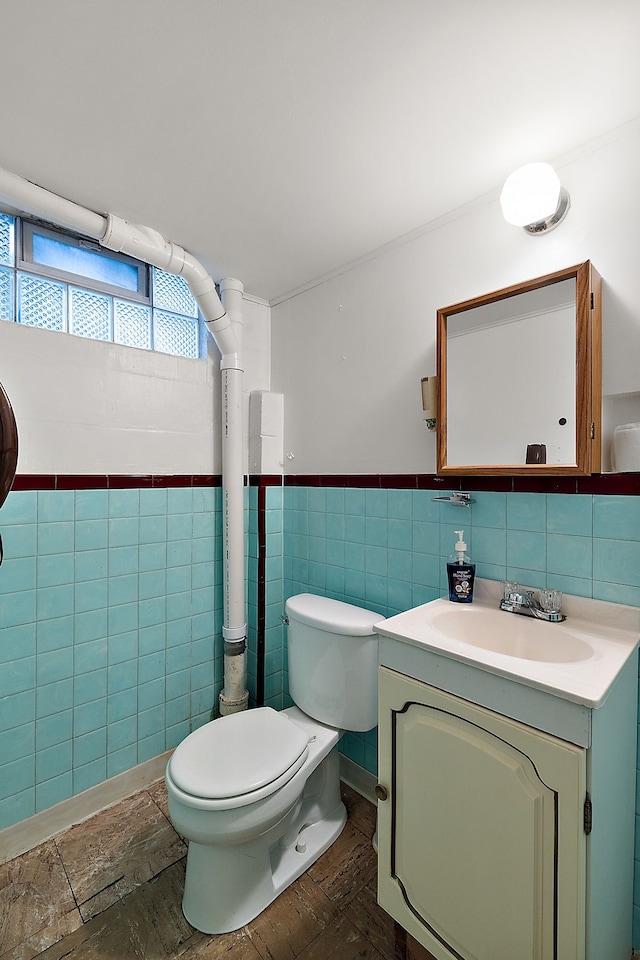 bathroom with vanity, tile walls, and toilet