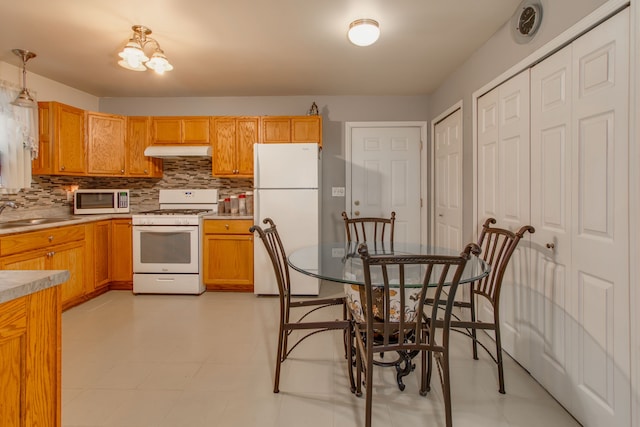 kitchen featuring sink, pendant lighting, white appliances, and decorative backsplash