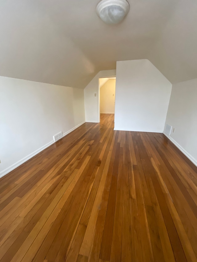 bonus room with hardwood / wood-style flooring and vaulted ceiling