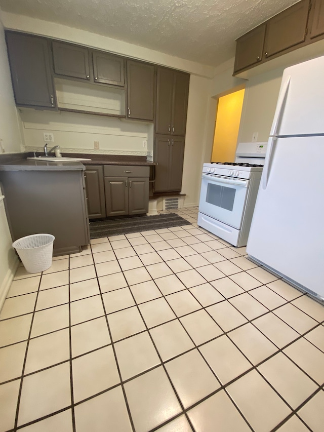 kitchen featuring sink, a textured ceiling, and white appliances