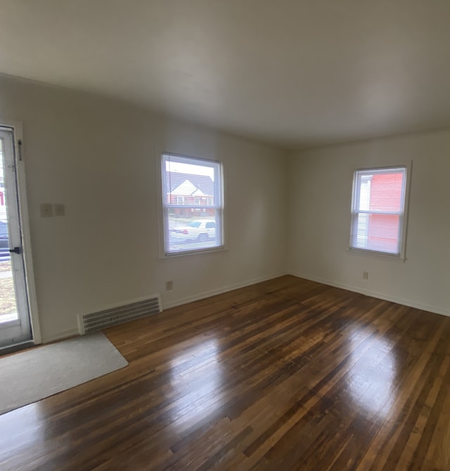 empty room with plenty of natural light and dark hardwood / wood-style flooring