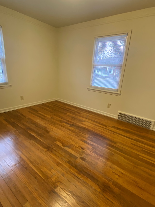 empty room with ornamental molding and dark hardwood / wood-style flooring