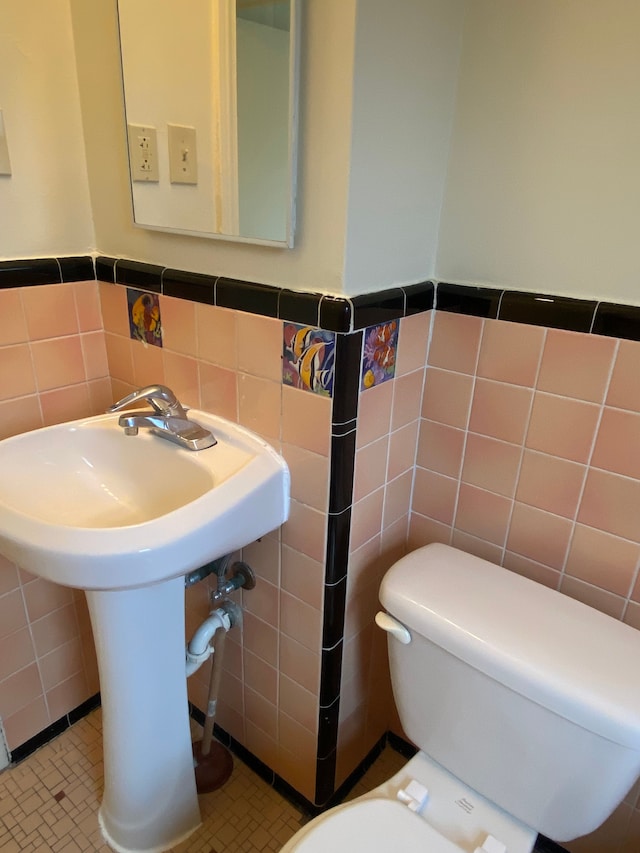 bathroom with tile patterned floors, toilet, and tile walls