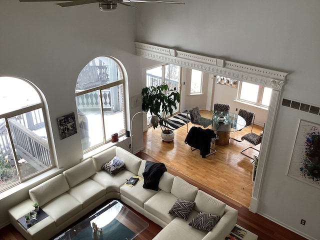 living room featuring wood-type flooring, plenty of natural light, a towering ceiling, and ceiling fan