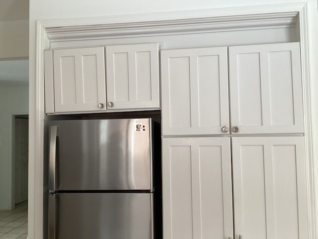 kitchen with stainless steel fridge, tile patterned floors, and white cabinets