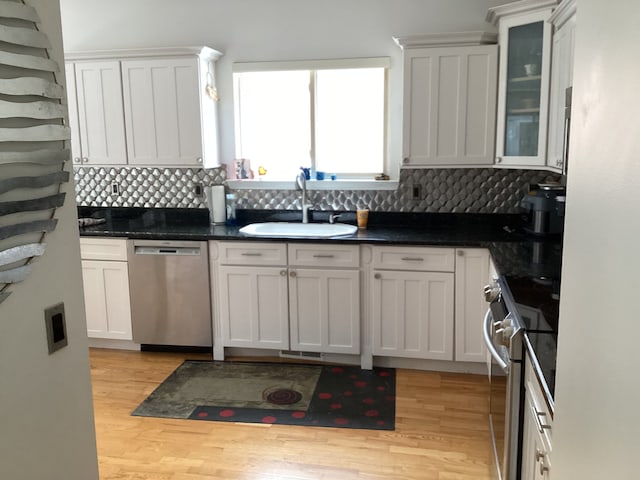 kitchen with sink, backsplash, white cabinets, and appliances with stainless steel finishes