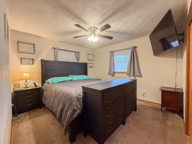 bedroom featuring ceiling fan, light colored carpet, and a textured ceiling