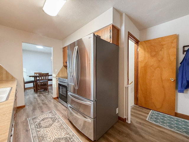 kitchen with appliances with stainless steel finishes, sink, and light hardwood / wood-style flooring