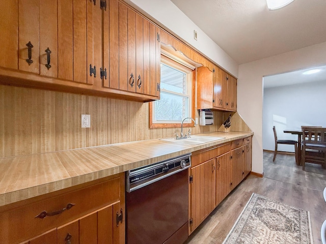 kitchen with black dishwasher, sink, backsplash, and light hardwood / wood-style flooring