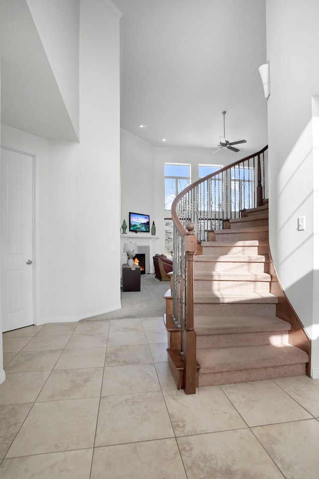 stairs with tile patterned flooring, a towering ceiling, and ceiling fan