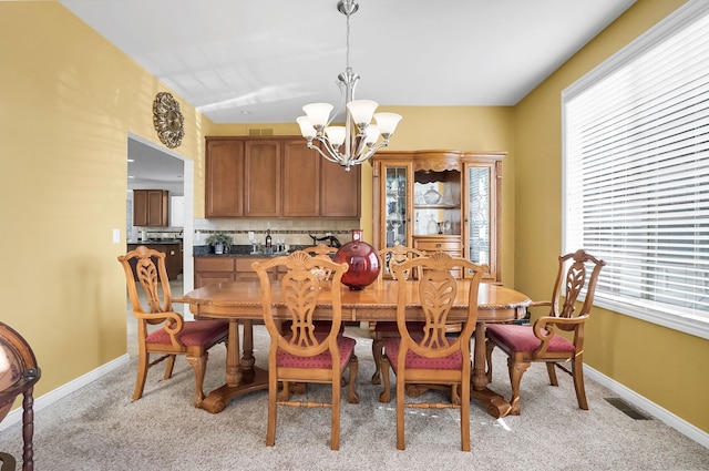 carpeted dining space with an inviting chandelier