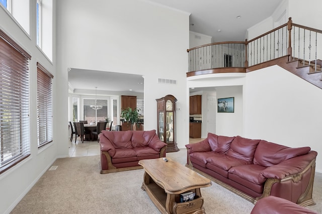 carpeted living room featuring ornamental molding, an inviting chandelier, and a towering ceiling