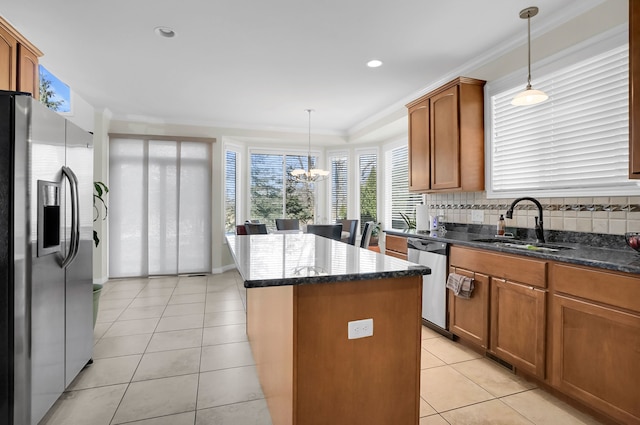 kitchen with appliances with stainless steel finishes, decorative backsplash, pendant lighting, a center island, and sink