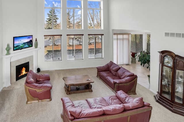 tiled living room featuring a premium fireplace and a high ceiling