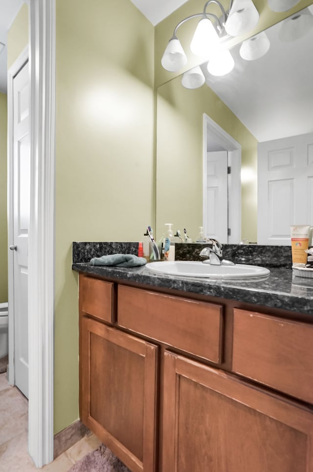 bathroom featuring tile patterned floors, toilet, vanity, and a notable chandelier