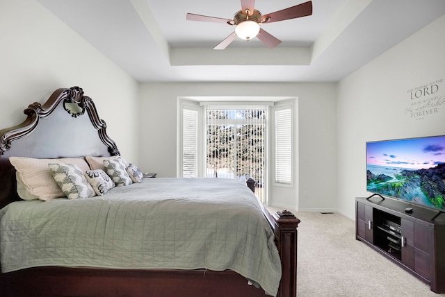 bedroom with a tray ceiling, light colored carpet, and ceiling fan