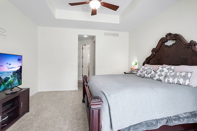 carpeted bedroom featuring a tray ceiling and ceiling fan