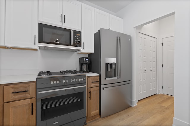 kitchen featuring appliances with stainless steel finishes, light hardwood / wood-style flooring, and white cabinets