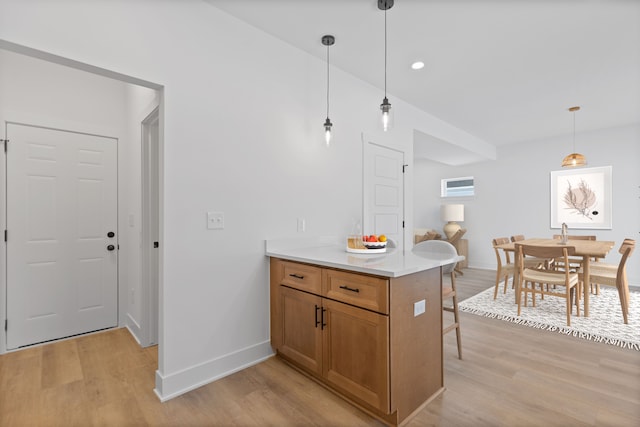 kitchen with a breakfast bar area, kitchen peninsula, light hardwood / wood-style floors, and hanging light fixtures