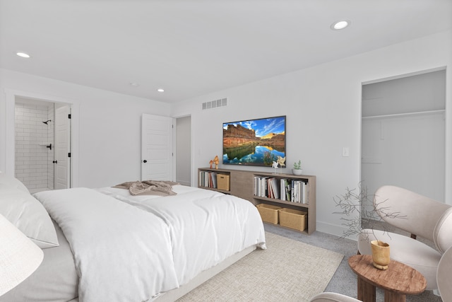 bedroom with ensuite bath, a spacious closet, and carpet floors