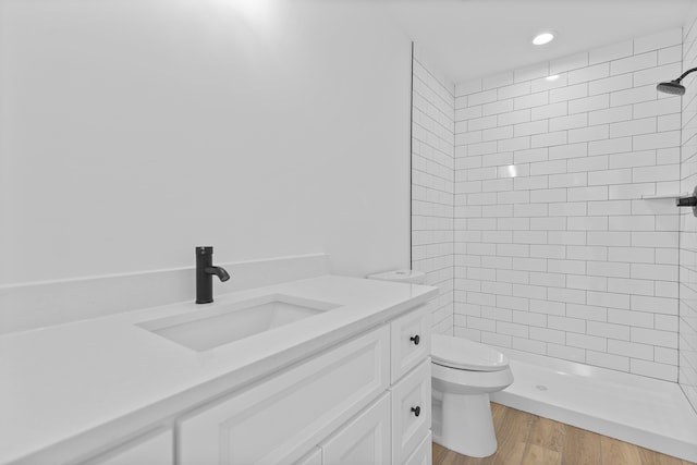 bathroom with vanity, toilet, wood-type flooring, and a tile shower