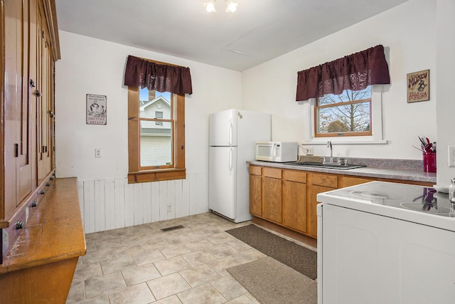 kitchen with sink, wooden walls, and white appliances