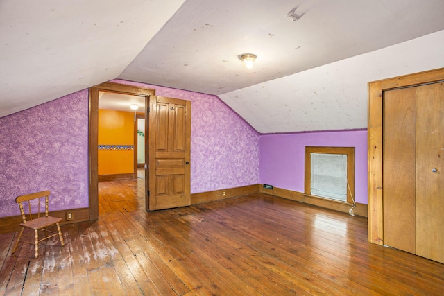 additional living space with hardwood / wood-style flooring and lofted ceiling