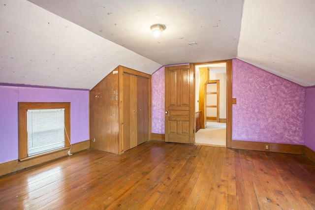 additional living space with hardwood / wood-style flooring and vaulted ceiling