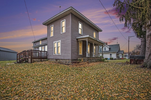 back house at dusk featuring a yard and a deck