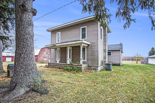 view of front facade featuring a porch, cooling unit, and a front yard