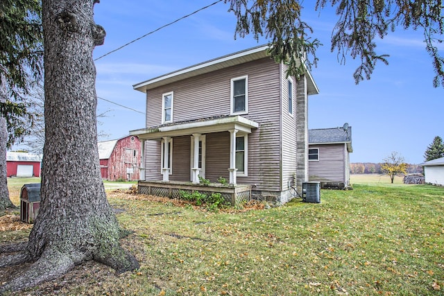 view of front facade featuring a porch, cooling unit, and a front yard