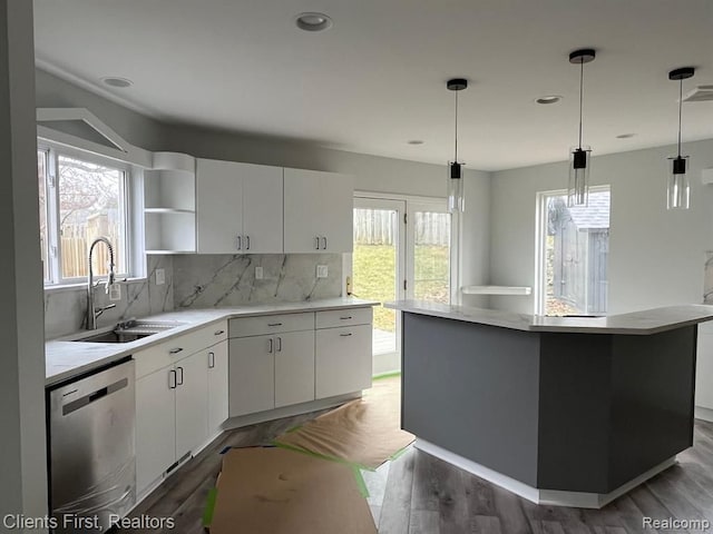 kitchen with sink, dishwasher, white cabinetry, a kitchen island, and decorative light fixtures