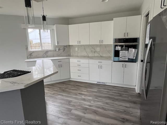 kitchen with hardwood / wood-style flooring, appliances with stainless steel finishes, decorative backsplash, white cabinets, and decorative light fixtures