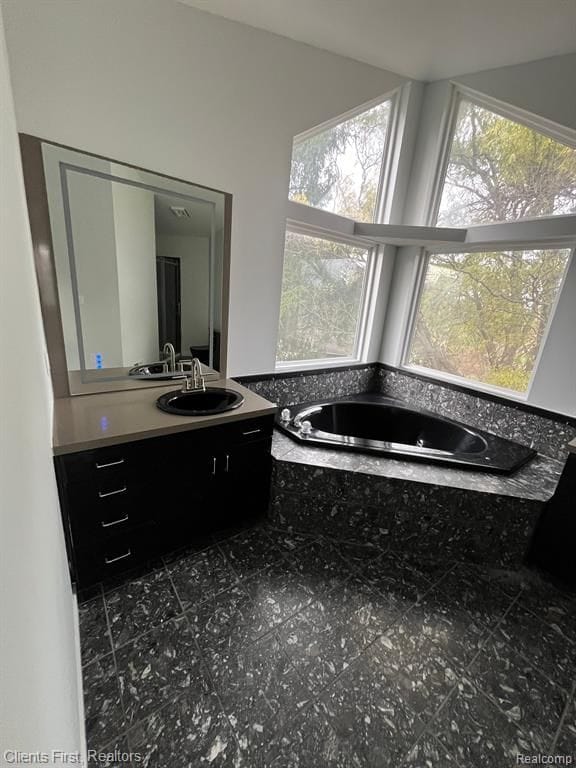 bathroom featuring tiled tub and vanity