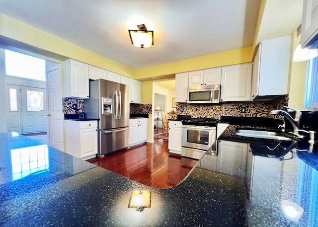 kitchen featuring backsplash, appliances with stainless steel finishes, white cabinets, and a sink