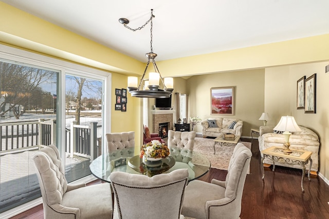 dining area featuring dark wood-type flooring, a fireplace, and baseboards