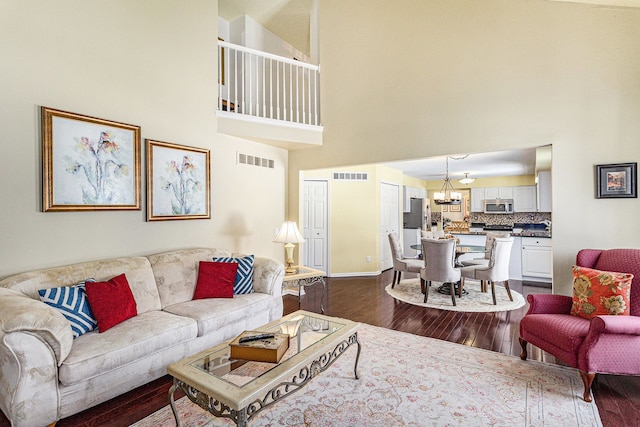 living area with visible vents, dark wood finished floors, and a notable chandelier