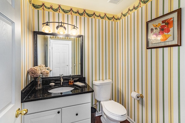 bathroom featuring toilet, wallpapered walls, visible vents, and vanity