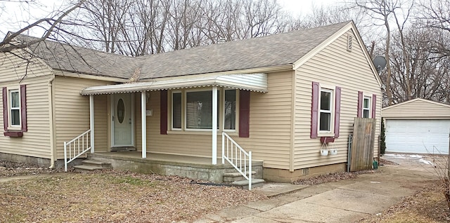 bungalow with a garage, roof with shingles, and an outdoor structure