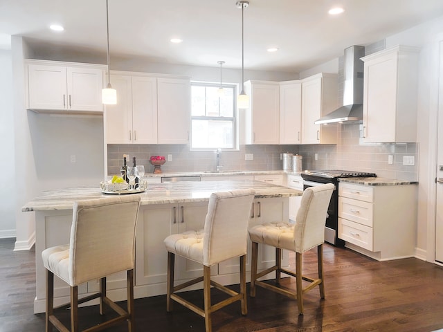 kitchen featuring appliances with stainless steel finishes, pendant lighting, white cabinets, and wall chimney exhaust hood