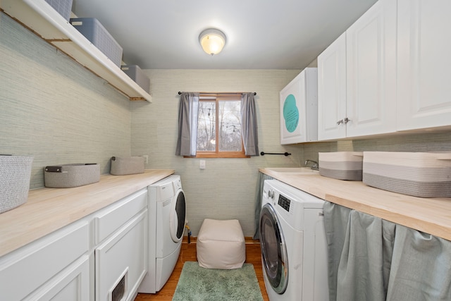 laundry room with cabinets, washing machine and dryer, sink, and light wood-type flooring