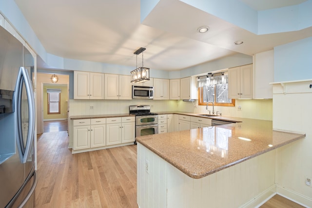 kitchen with decorative light fixtures, sink, stainless steel appliances, and kitchen peninsula