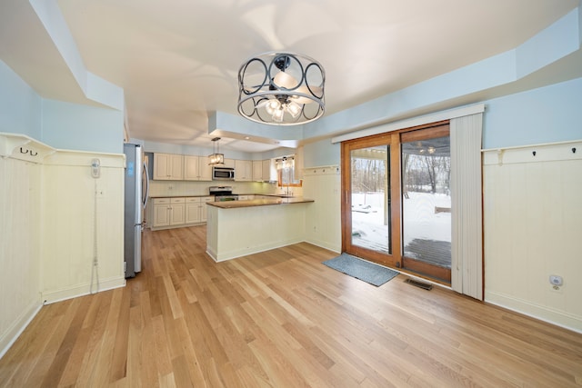 kitchen featuring kitchen peninsula, hanging light fixtures, stainless steel appliances, and light hardwood / wood-style floors