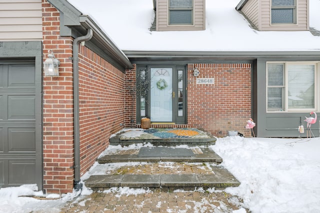 snow covered property entrance with a garage