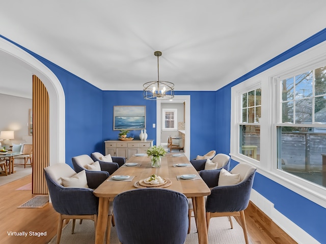 dining space with light hardwood / wood-style flooring and a chandelier