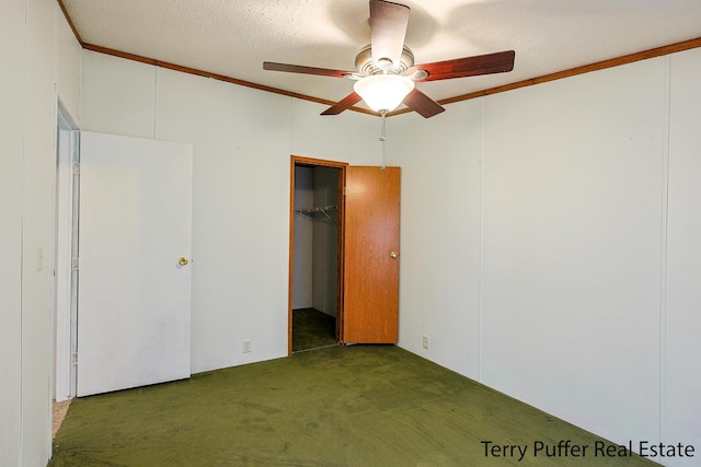 unfurnished bedroom featuring ceiling fan, a textured ceiling, dark carpet, a walk in closet, and a closet