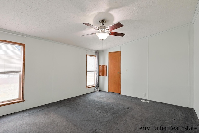 spare room with dark colored carpet, ceiling fan, and a textured ceiling