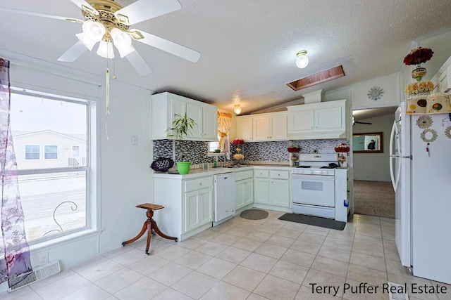 kitchen with lofted ceiling, white cabinetry, plenty of natural light, white appliances, and decorative backsplash