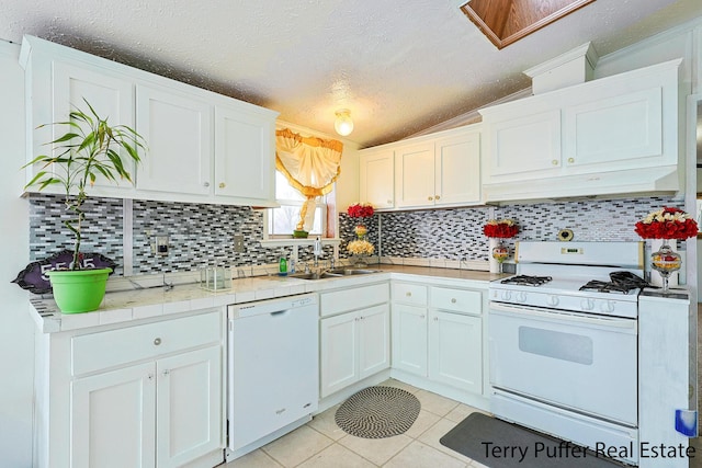 kitchen with tasteful backsplash, white cabinetry, sink, light tile patterned floors, and white appliances